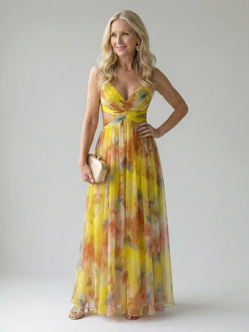 Woman wearing a yellow watercolour print maxi dress with wrap bodice, posing with hand on hip