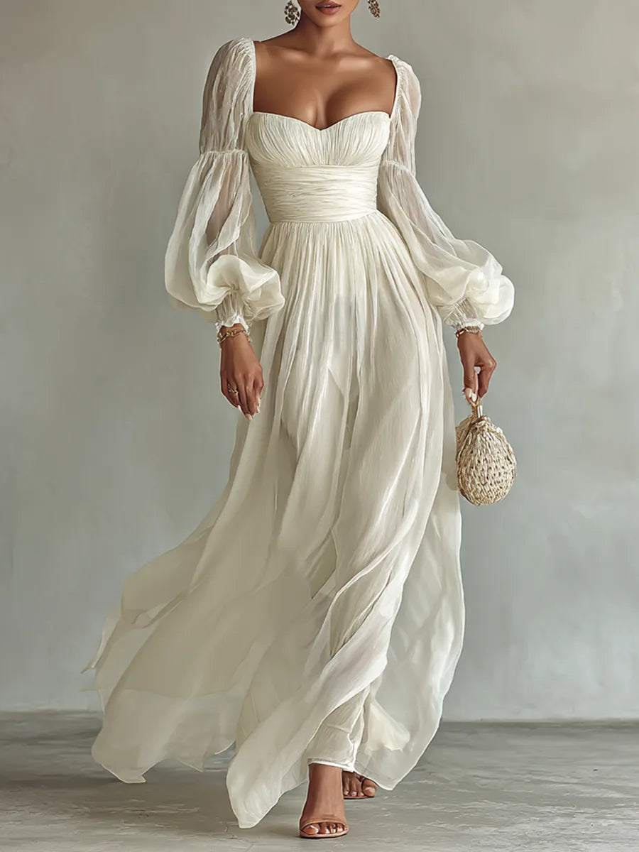 Model wearing a white chiffon maxi dress with sweetheart neckline, ruched waist and sheer balloon sleeves, holding a woven bag