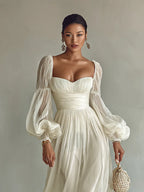 Close front view of the square sweetheart neckline, ruched bodice and sheer puff sleeves on a white chiffon maxi dress