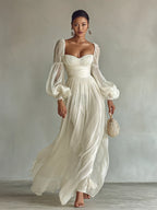 Full-length front view of the white chiffon maxi dress styled with strappy heeled sandals and statement earrings