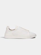 Side profile of a white leather low-top sneaker with elastic laced vamp and ridged white rubber sole.