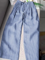 Soft blue wide-leg pants with pintuck waist detail and drawstring tie, laid flat