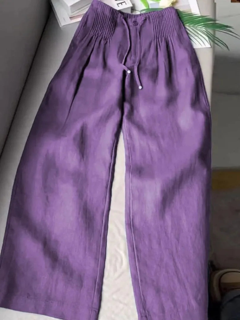 Purple wide-leg pants with pintuck elastic waist and drawstring, laid flat on a couch