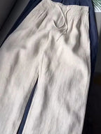 Apricot beige pants folded over navy pair, showing pintuck waist and drawstring detail