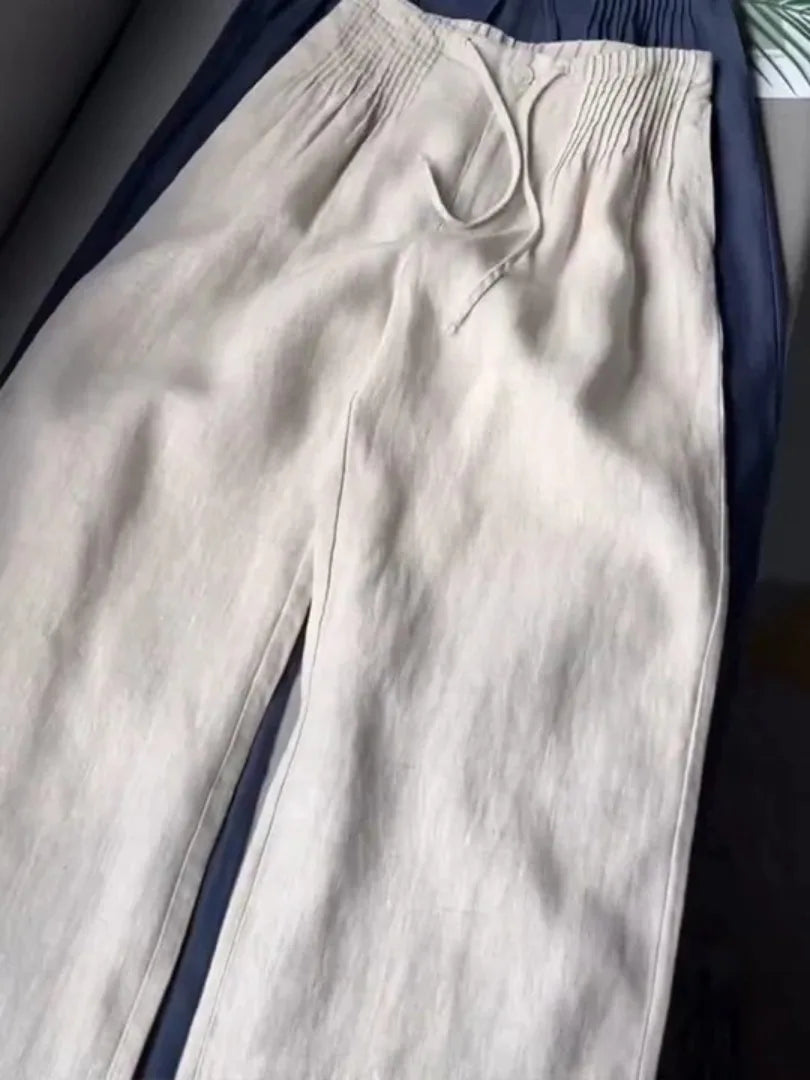 Apricot beige pants folded over navy pair, showing pintuck waist and drawstring detail