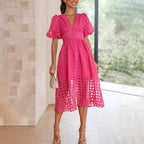 Woman wearing a hot pink windowpane-check puff-sleeve midi dress with a deep V-neckline and button front, standing indoors.