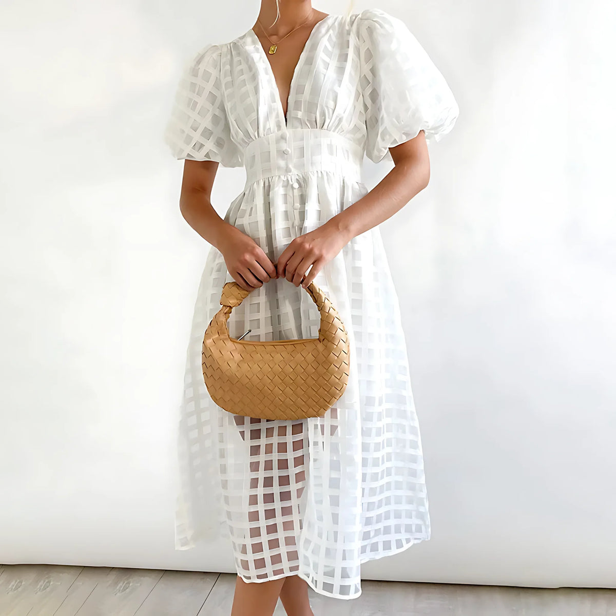White windowpane-check midi dress with puff sleeves and a fitted button-front waist, worn with a woven top-handle bag.