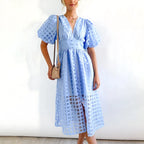 Light blue sheer windowpane-check midi dress with puff sleeves, a V-neckline and side slit, shown from the front.