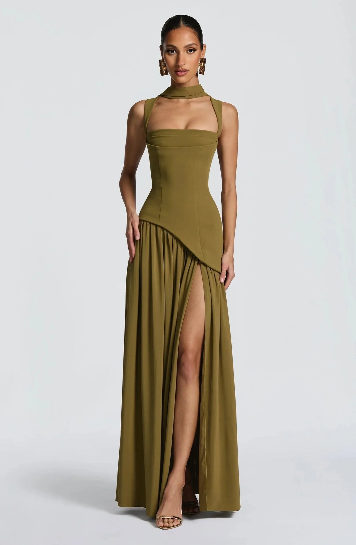 Front view of model in an olive green sleeveless maxi dress with fitted corset bodice and flowing asymmetric skirt