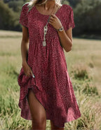 Red polka dot midi dress with round neckline and short sleeves, styled with a long layered necklace