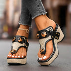 Side view of black strappy wedge sandals on woven platform, gold studded ankle strap with tortoiseshell accent