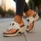 Close-up of ivory white strappy wedge sandal with gold studs and tortoiseshell buckle detail
