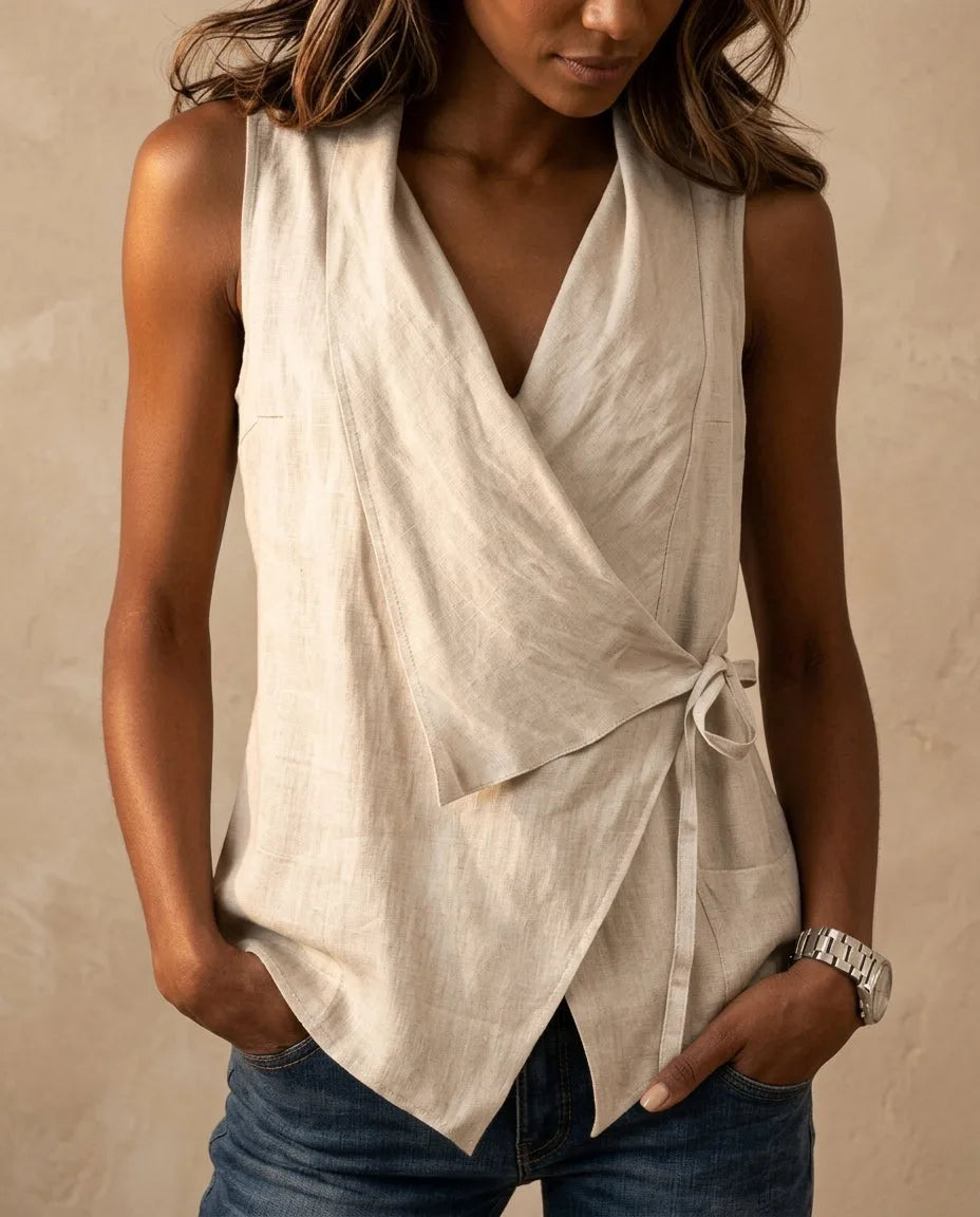 Close-up of an oatmeal linen wrap-front tank top with V neckline and side tie, worn over denim jeans.