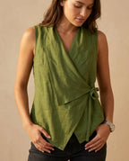 Olive green wrap-style sleeveless top with asymmetrical hem shown against a plain studio backdrop.
