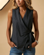 Black linen-look wrap tank top with V neckline and tied waist, paired with dark denim jeans.