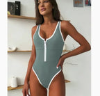 Sage green one-piece swimsuit with white contrast trim and front zip, square neckline, studio shoot