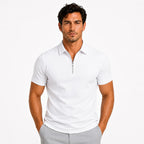 Front view of a man wearing a white zip-neck slim-fit polo shirt with the zip partially open, paired with grey pants
